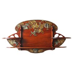 an ornate wooden tray with metal decorations on the top and bottom, hanging from a wall