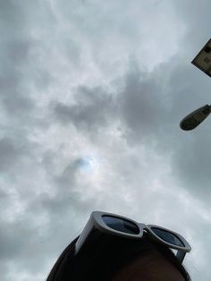 a woman wearing sunglasses looking up at the sky with clouds in the background and an airplane flying overhead