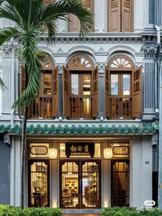 the front entrance to a building with palm trees in front of it and windows on both sides