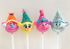 four cake pops with faces on them in the shape of clowns, one wearing a hat