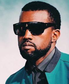 a man wearing sunglasses and a green shirt is looking off to the side in front of a blue background