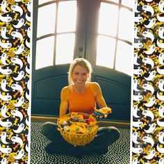 a woman sitting on the floor holding a basket full of food in front of her