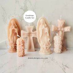 three candles are shown with the names of each candle in front of them and an angel statue next to it