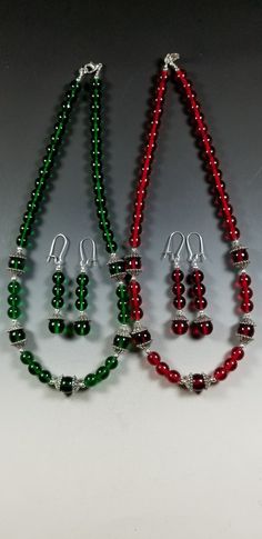 This pretty Necklace and Earrings set is available in your Choice of Emerald Green or Ruby Red.   The necklace is made with 8mm Translucent Czech Glass Beads highlighted with 10mm beads surrounded with Tibetan Silver Bead Caps. The overall length is 18 inches. It's strung on heavy duty tiger tail for strength and is finished off with a silver plated Lobster Claw clasp and Jump Ring. The matching earrings are 1-3/4 inches long ( not including the silver plated kidney shaped ear wires) and are lig Glass Stone Jewelry, Christmas Bead Necklace, Tiger Tail, Czech Glass Necklace, Genuine Pearl Necklace, Christmas Jewellery, Stone Bead Jewelry, Beads Craft Jewelry, Pretty Jewelry Necklaces