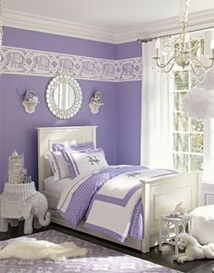 a purple and white bedroom with chandelier, bedding, rugs and pillows