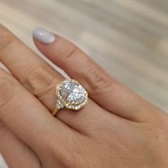 a woman's hand holding an engagement ring with a large diamond in the center