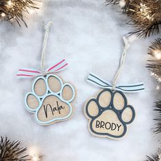 two personalized wooden ornaments hanging from a christmas tree with dog paw prints on them