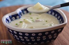 a spoonful of soup in a blue and white bowl on top of a wooden table