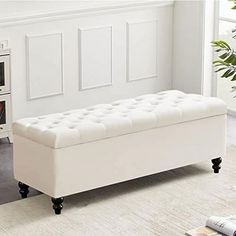 a white bench sitting on top of a carpeted floor next to a plant in a living room