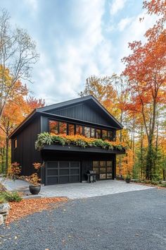 a black house with lots of windows and plants on the roof, surrounded by fall foliage