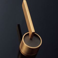 a close up of a metal object on a black surface with a wooden stick sticking out of it