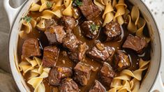 a pot filled with beef and noodles on top of a table