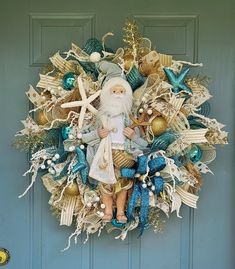 a christmas wreath with a santa clause holding a starfish and seashells in front of a blue door