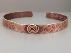 Bangle in hand hammered copper  It features a spiral emblem which is based on carvings found at New Grange. Artisan Hammered Bronze Bracelets, Unique Hammered Copper Bracelets, Copper Wire Jewelry, Hand Saw, Hammered Copper, Leaf Pendant, Diy Bracelets, Copper Wire, Wire Jewelry