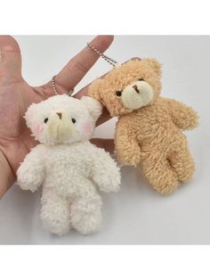 two teddy bears being held in the palm of someone's hand, on a white background