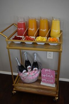 a gold bar cart filled with different types of juices and condiments on it