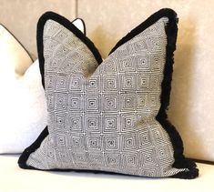 a black and white pillow sitting on top of a couch next to two pillows in the shape of squares