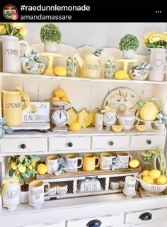 a white dresser topped with lots of lemons next to a shelf filled with cups and saucers