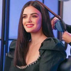 a woman is getting her hair done with a blow dryer