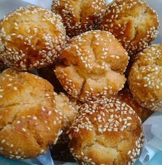 sesame seed muffins in a plastic container on top of a blue table cloth