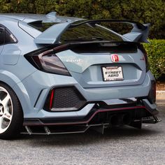 the rear end of a blue honda civic hatchback parked in a parking lot next to bushes