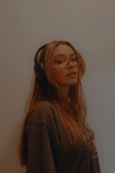 a woman with headphones standing in front of a wall