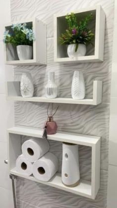 three white shelves holding toilet paper and vases