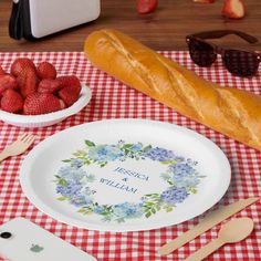 a table topped with plates and bowls filled with strawberries next to a loaf of bread