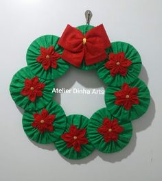 a green wreath with red poinsettis and a bow