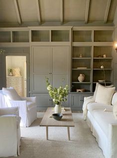 a living room filled with white furniture and lots of bookshelves on the wall