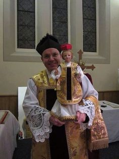 a priest is holding a doll in his arms