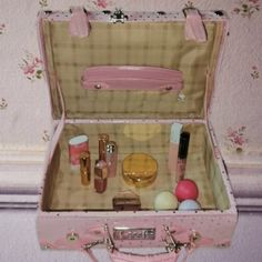 an open pink suitcase sitting on top of a table next to a wallpapered wall