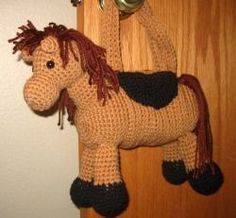 a crocheted toy horse hanging from a hook on a door handle next to a white wall