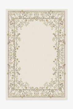 a white and beige rug with an ornate border on the bottom, surrounded by flowers