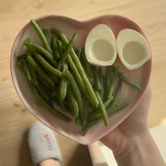 a heart shaped bowl filled with green beans and two halves cut in the shape of a heart