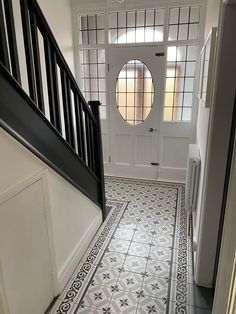 an entry way leading to a white door with black trim and decorative tile on the floor