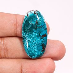 a hand holding a piece of turquoise colored stone