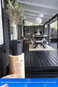 an outdoor deck with table, chairs and potted olive tree in the center area