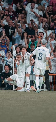 the soccer players are celebrating their team's goal in front of an excited crowd