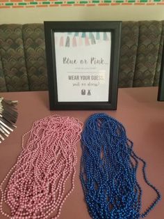 two necklaces are sitting on a table next to a framed sign that says please or pink and wear your guess