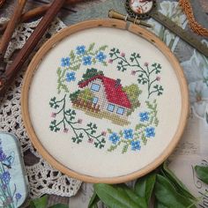 a cross stitch pattern with a house and flowers in the center, surrounded by other items