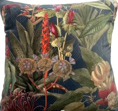 a blue pillow with flowers and leaves on the front, along with other tropical plants