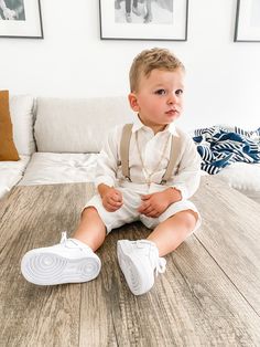 a little boy sitting on top of a wooden floor next to a white couch in a living room