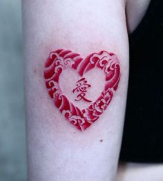 a heart shaped tattoo with chinese writing on the back of a woman's arm