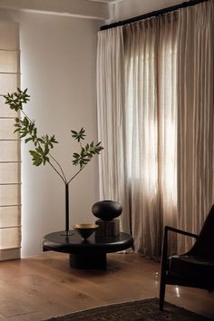 a living room with a chair, table and potted plant