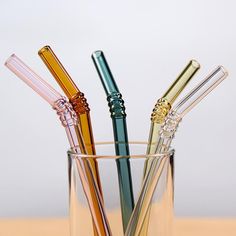 four different colored straws in a glass on a table