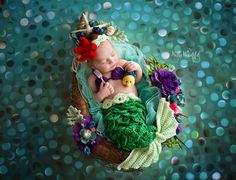 a baby doll is sleeping in a basket with flowers on the bottom and green fabric