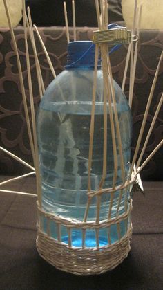 a plastic bottle with sticks sticking out of it sitting on a table next to a couch