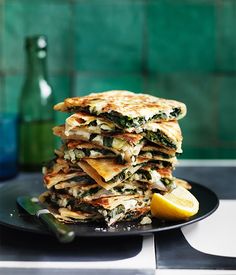 a stack of flatbreads on a plate with lemon wedges