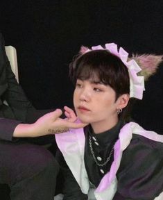 a person sitting in a chair with a cat ears on their head and one hand resting on his chin